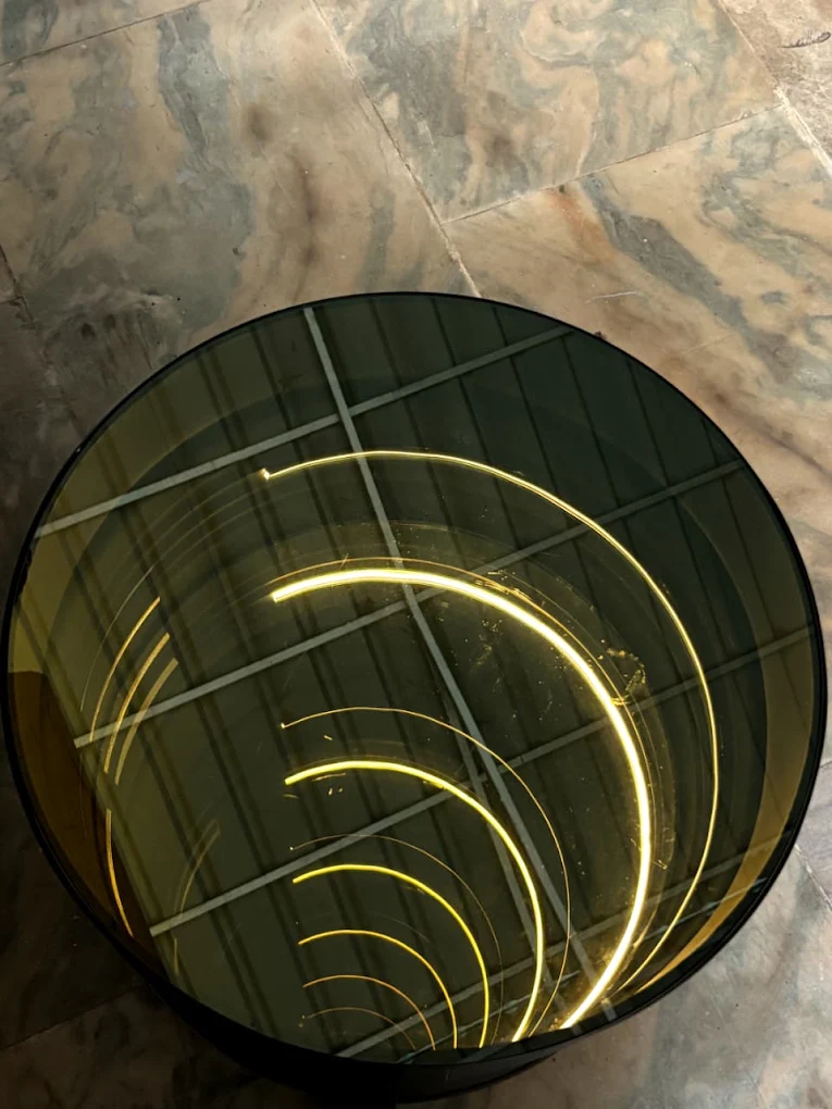 Top view of a drum coffee table's smoked-glass lid with LED spiral inside