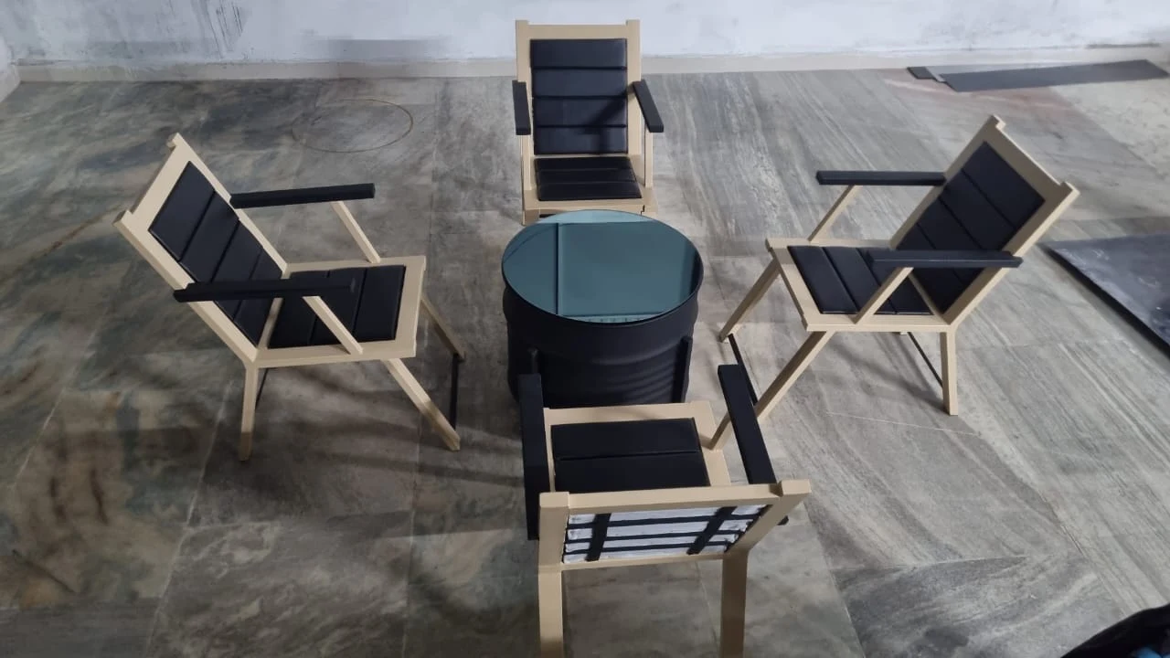 Set of cream-framed lounge chairs around a black drum coffee table with glass top