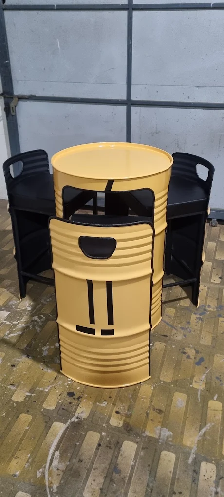 Mustard-yellow oil-drum table with black drum chairs tucked underneath