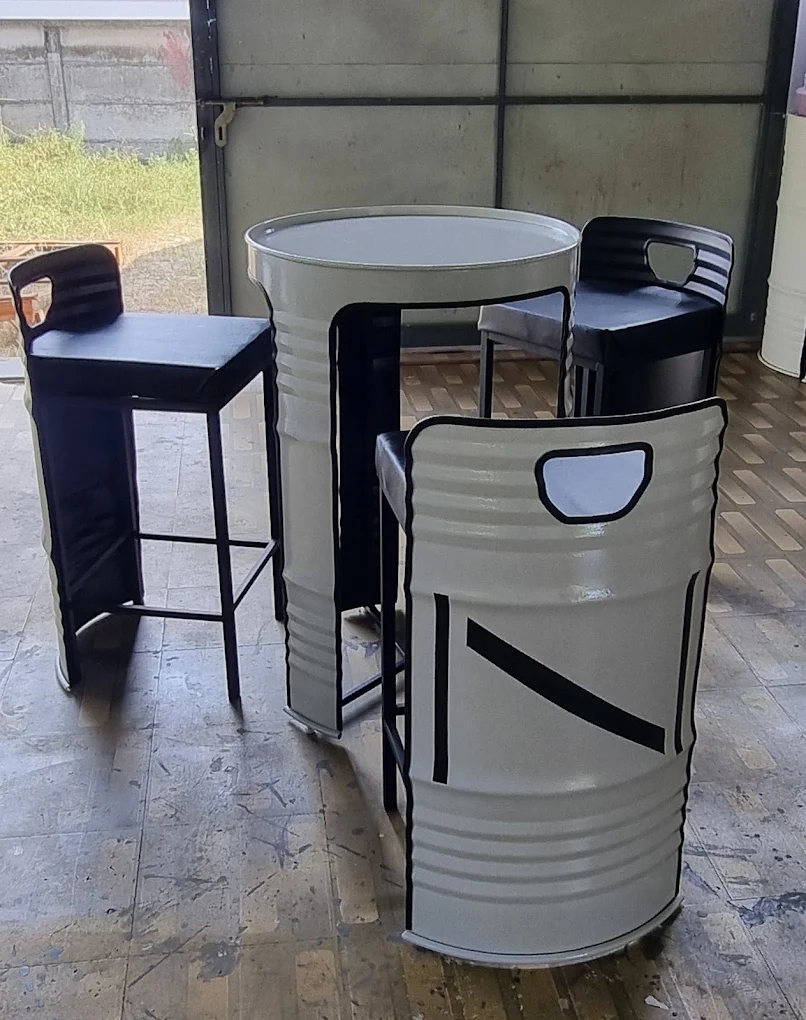 Cream oil-drum high table and drum chairs with a black bar stool in the Barrels workshop